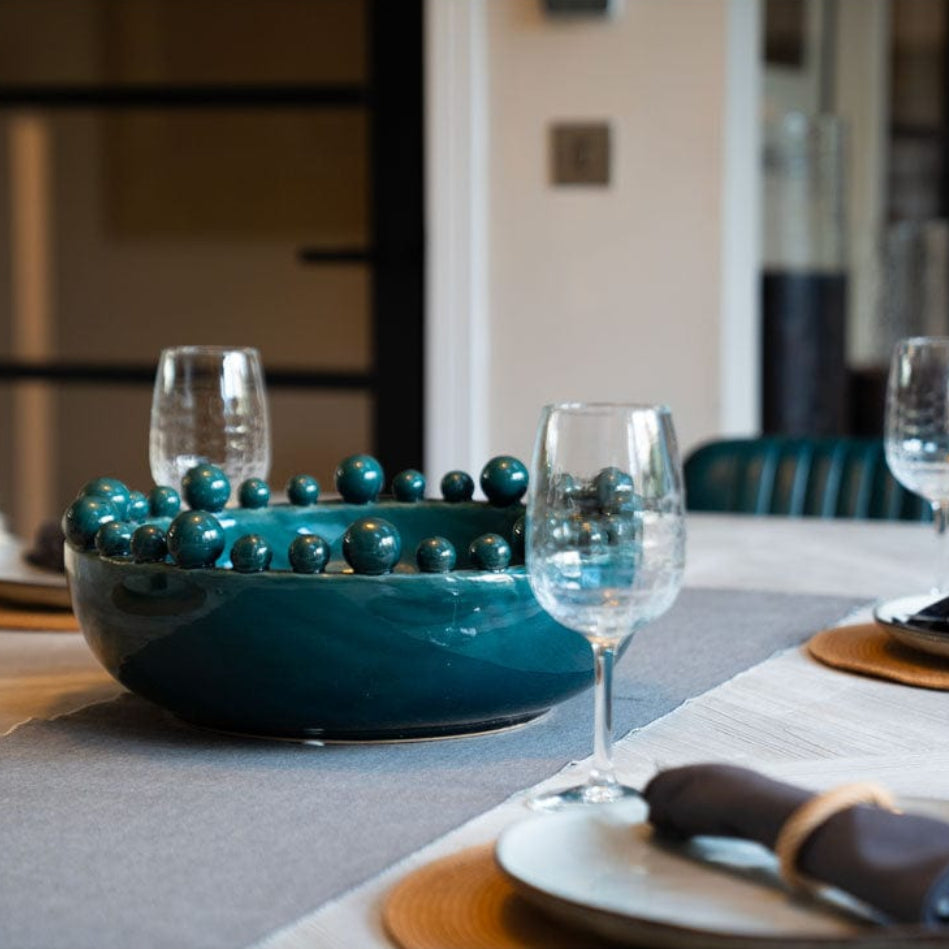 Table setting with teal bowl and wine glasses in a kitchen.