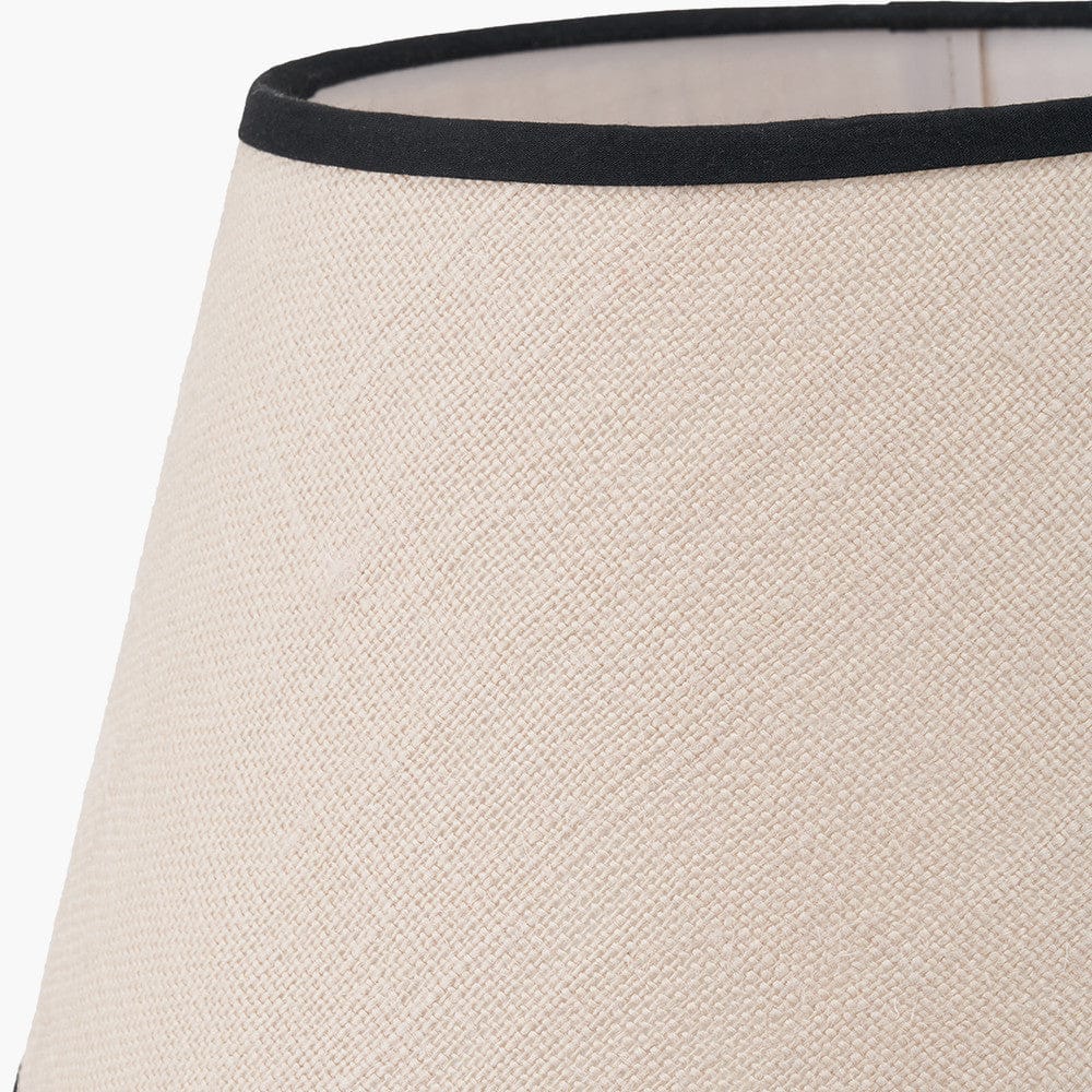 Close-up of a beige lampshade with a black band at the top on a white background