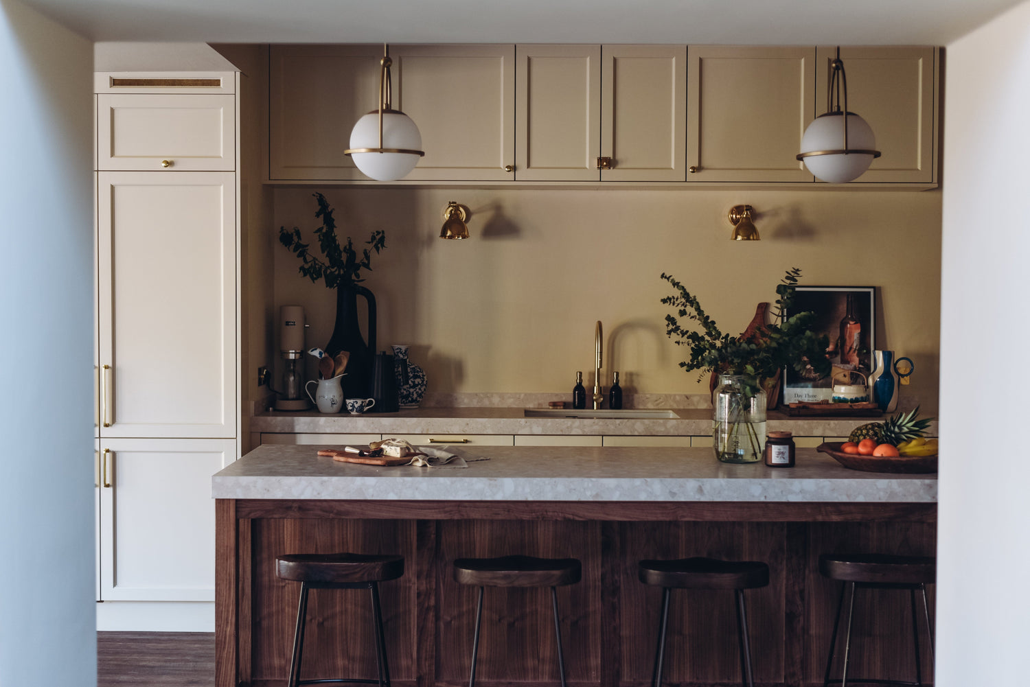 Modern kitchen with beige cabinets, marble island, and wooden stools.