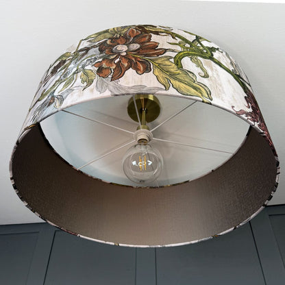 Floral-patterned lampshade with a light bulb inside on a plain background