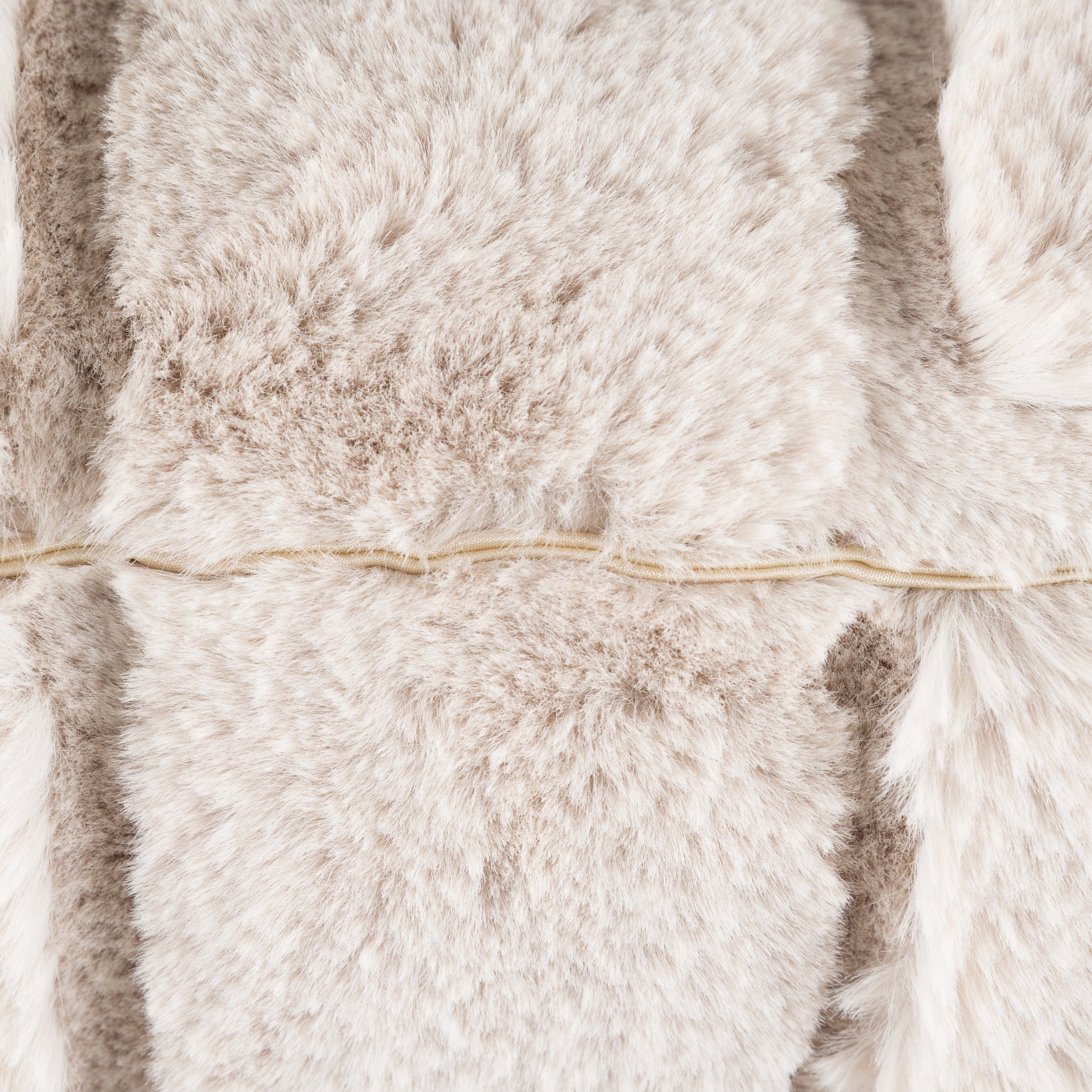 A close up of a soft fluffy beige cushion with a zip
