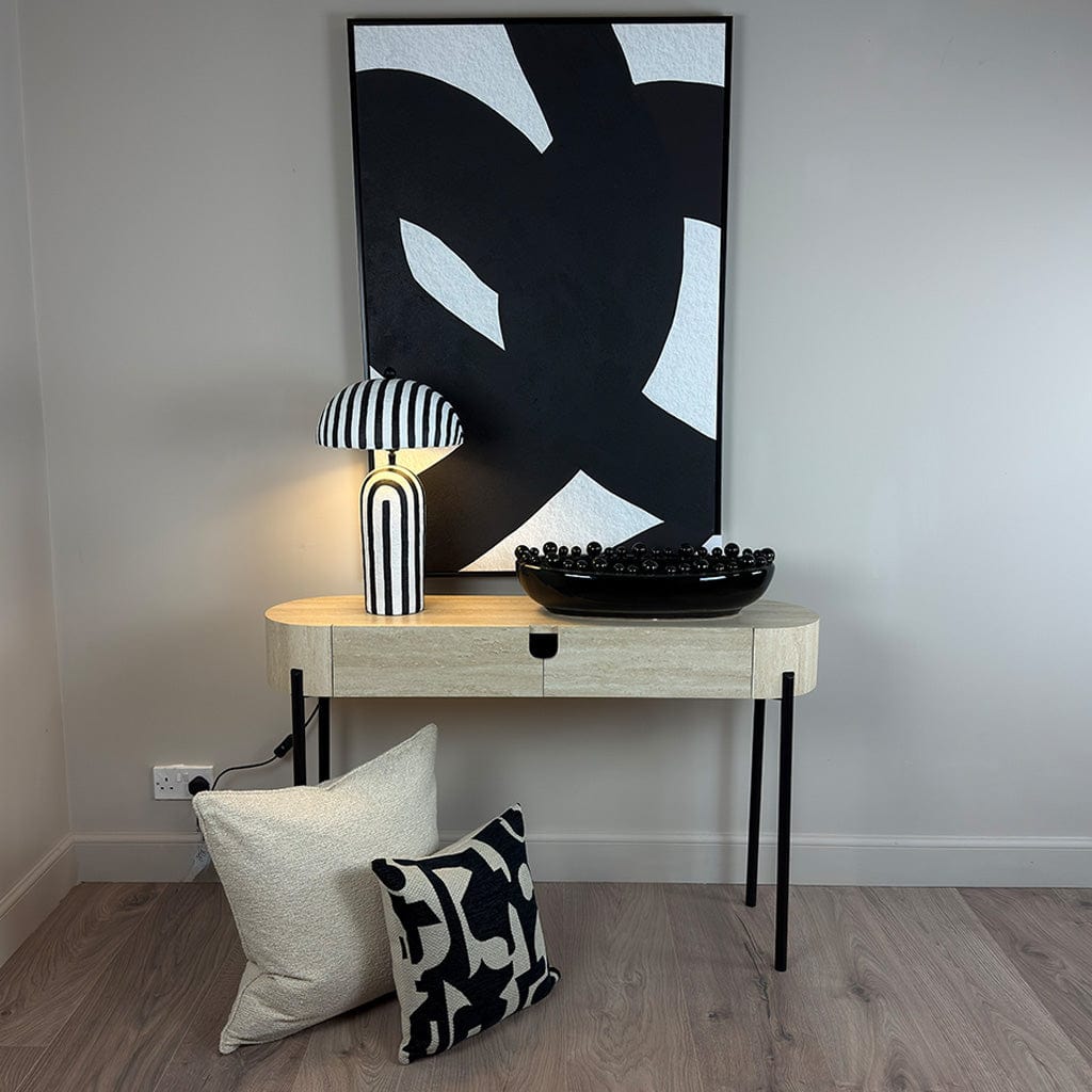 Modern interior with a console table, lamp, and abstract art on a gray wall.