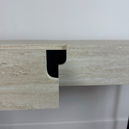 Close-up of a marble desk with a black corner piece against a white wall.