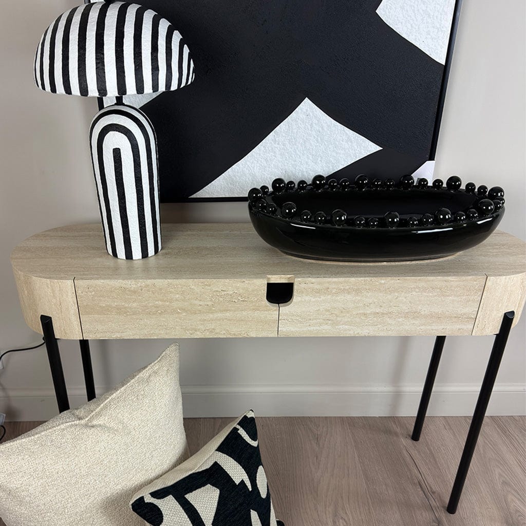 Modern interior with a console table, black and white striped lamp, and abstract art.