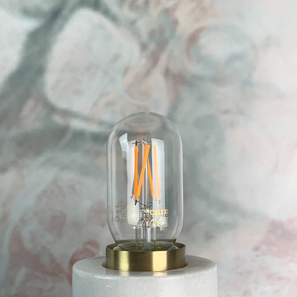 A clear tubular LED light bulb with visible filament, in a lamp holder