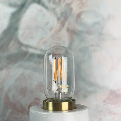 A clear tubular LED light bulb with visible filament, in a lamp holder