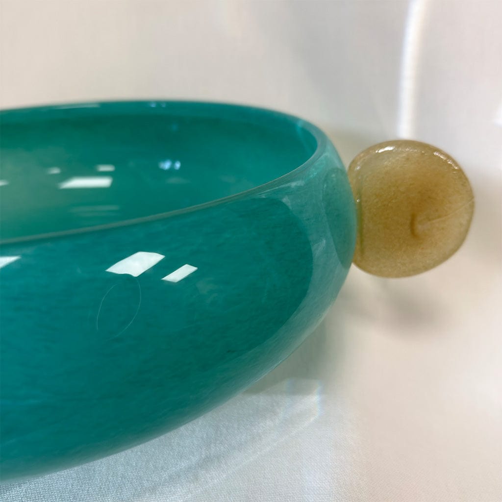 Teal ceramic bowl with a gold decorative element on a white background