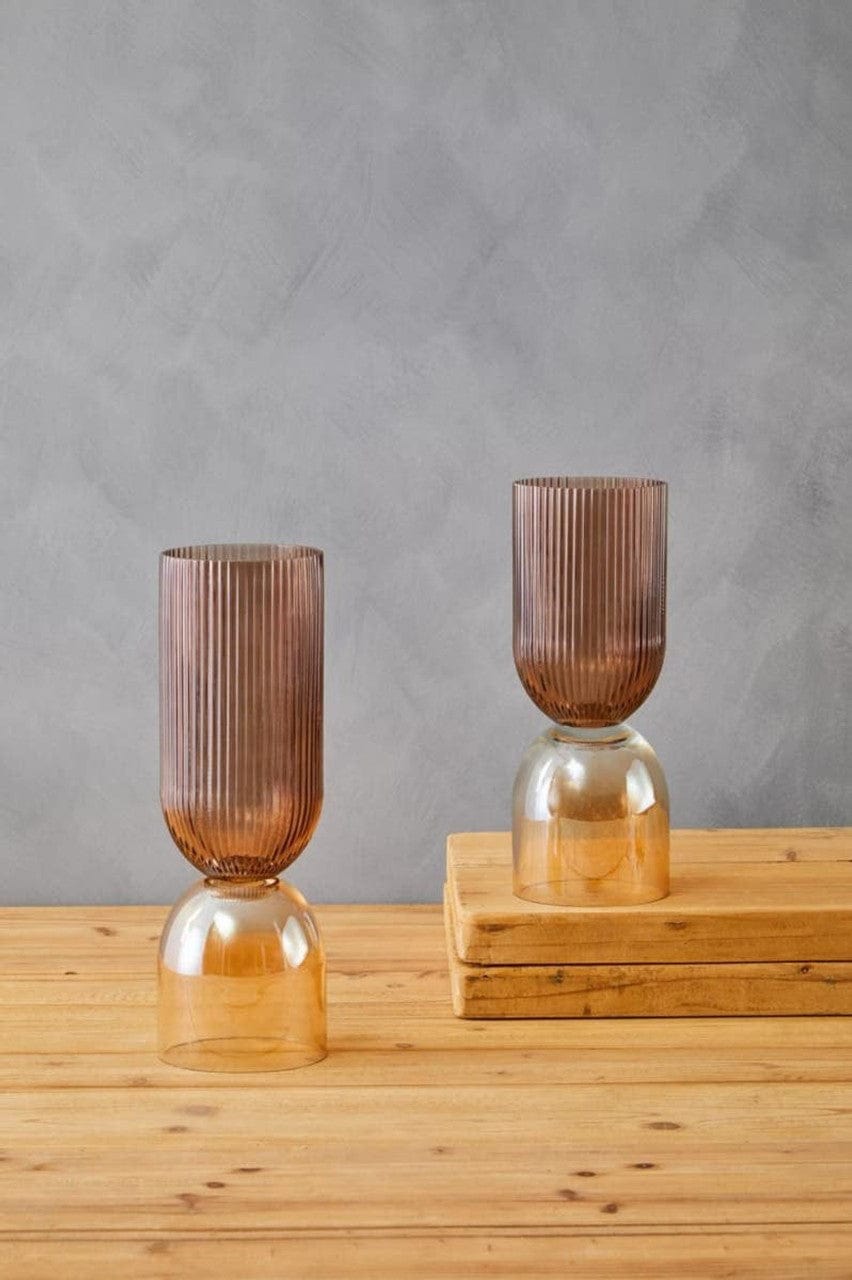 Two ribbed glass vases on a wooden surface with a gray background
