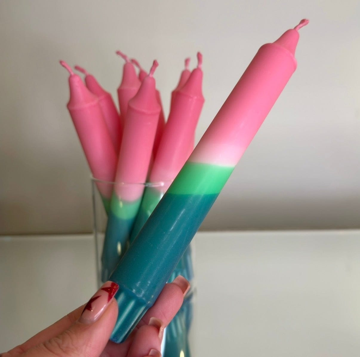 Pink and green candles with a hand holding one candle