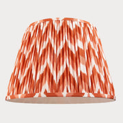 Lampshade with orange and white chevron pattern on a white background