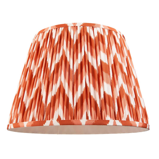 Lampshade with orange and white chevron pattern on a white background