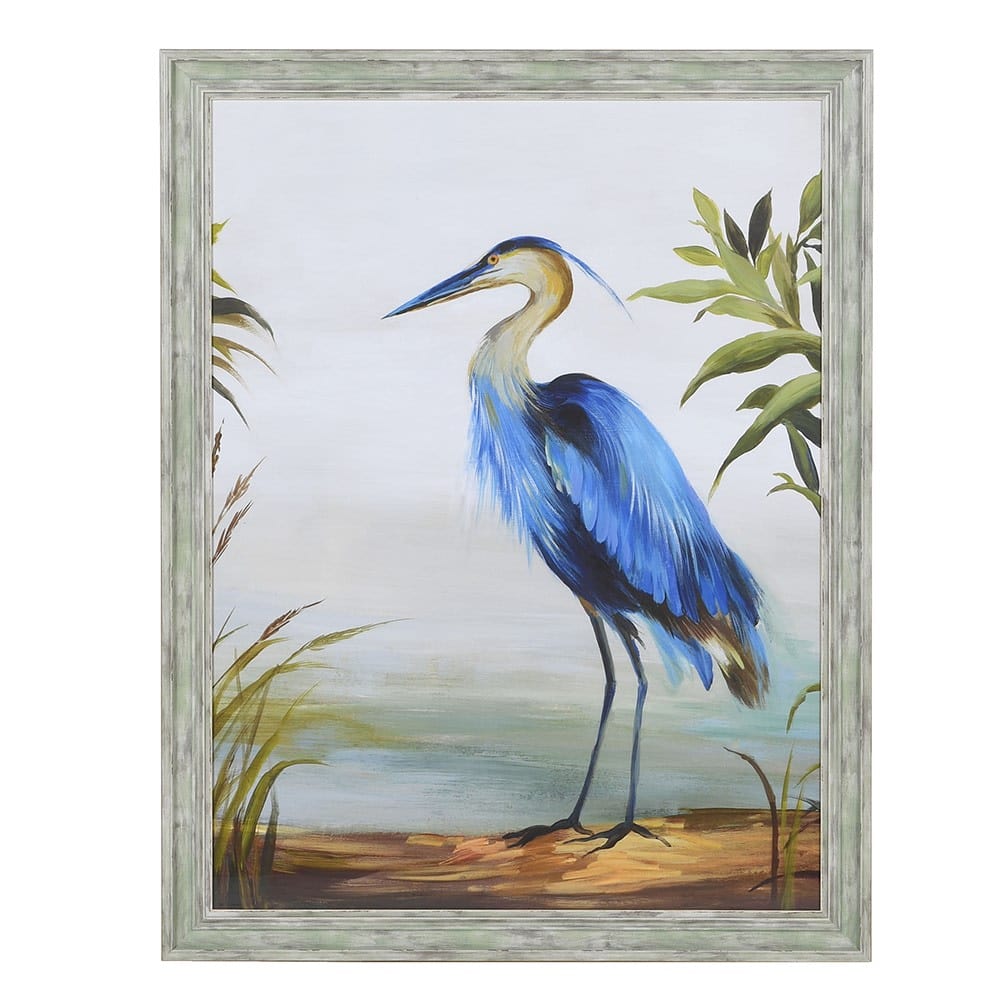 A framed print of a blue heron with blue tones on its feathers, standing among green foliage, in a distressed grey wooden frame.