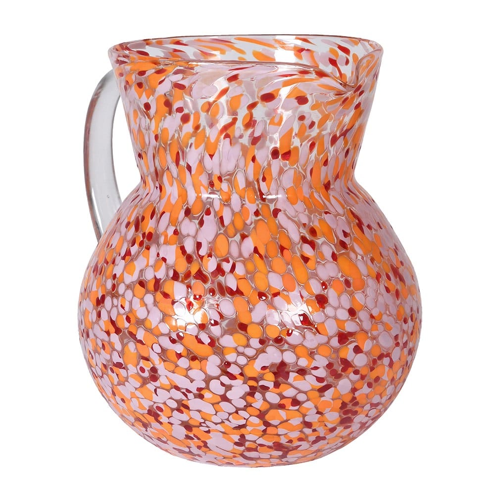A multicolored confetti glass jug with a geometric pattern, featuring shades of orange and pink against a white background.
