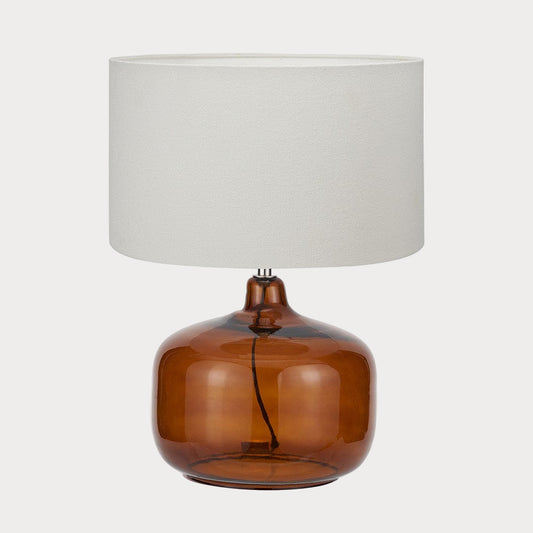Table lamp with brown glass base and white fabric shade on a white background