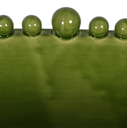 Close up of the edge of a shiny green ceramic bowl with bobbles around the edge