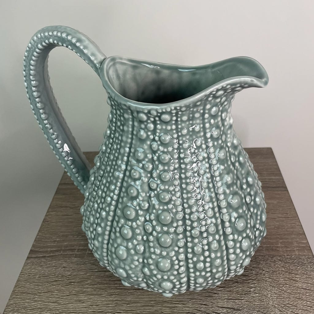 A large grey ceramic jug with a textured surface, resembling the shell of a sea urchin