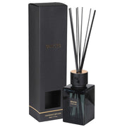 A black reed diffuser with clear glass bottle and black sticks, next to its black box packaging with gold accents.