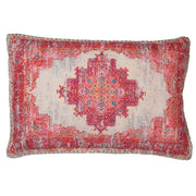 A rectangular cushion with a geometric pattern in red, pink, and orange tones, with a faded and distressed design resembling an Persian rug.