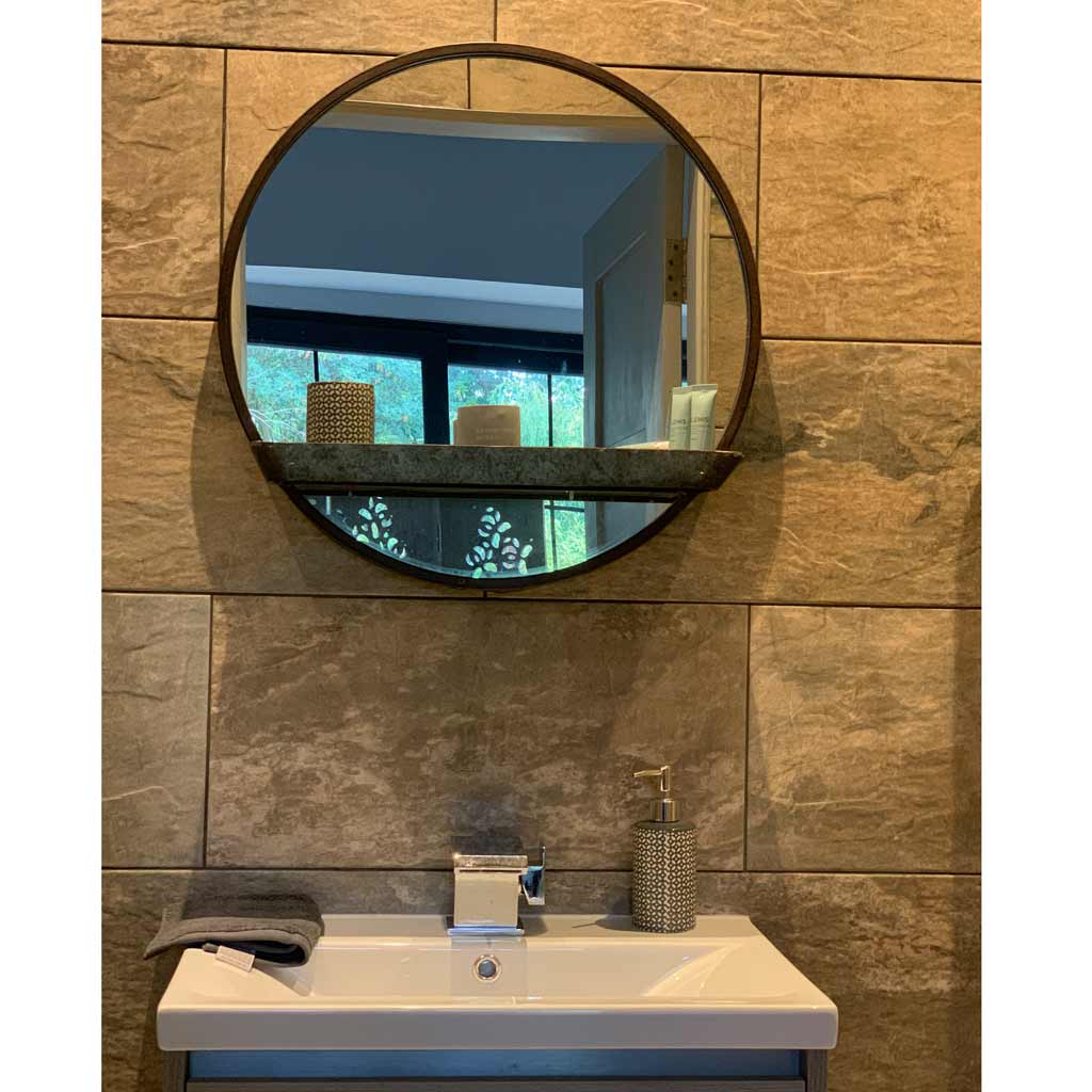 Round wall mirror with shelf on a tiled bathroom wall