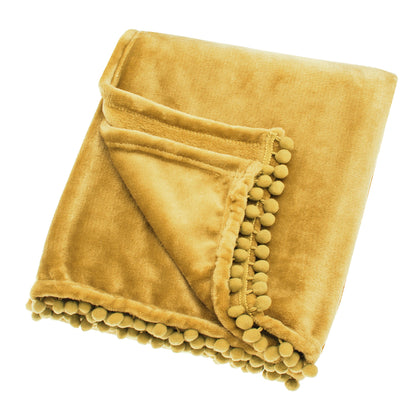 A saffron yellow fleece throw with pom pom trim unfolded and laying on a plain background.