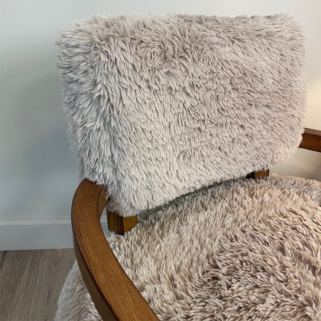 A caramel-colored faux fur armchair with dark ash wood arms.